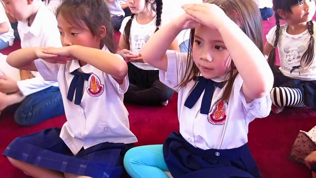 Children in school uniform giving a wai